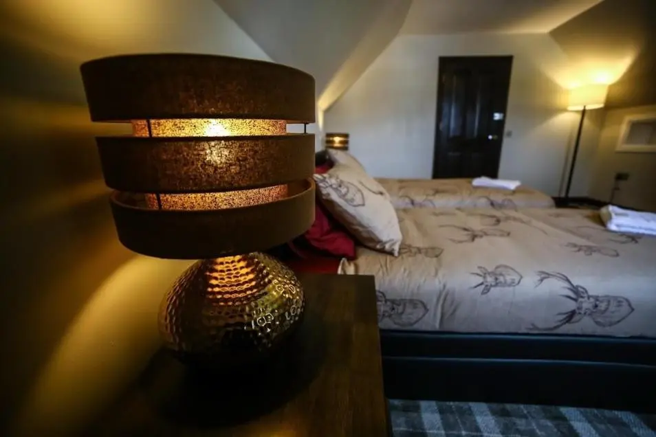 a lamp sitting on a table next to a bed at Whitehouse B&B in Fort Augustus