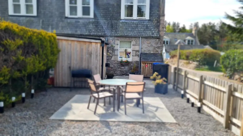 a patio with a table and chairs and a fence at Deeside Holiday Cottages in Dinnet