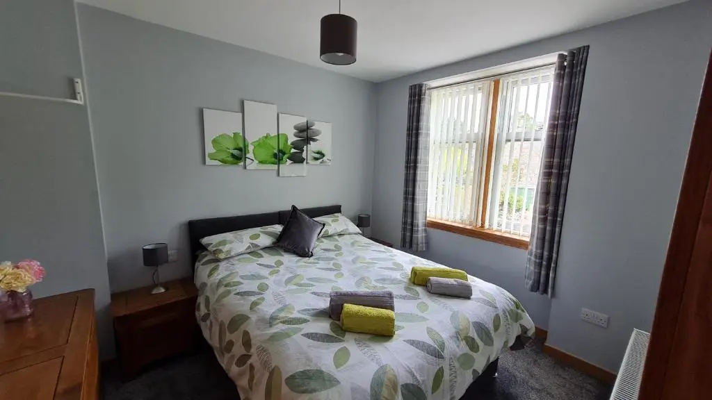 a bedroom with a bed with yellow pillows and a window at Deeside Holiday Cottages in Dinnet