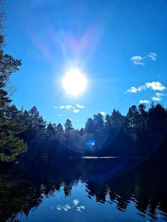 a view of a lake with the sun in the sky at Deeside Holiday Cottages in Dinnet