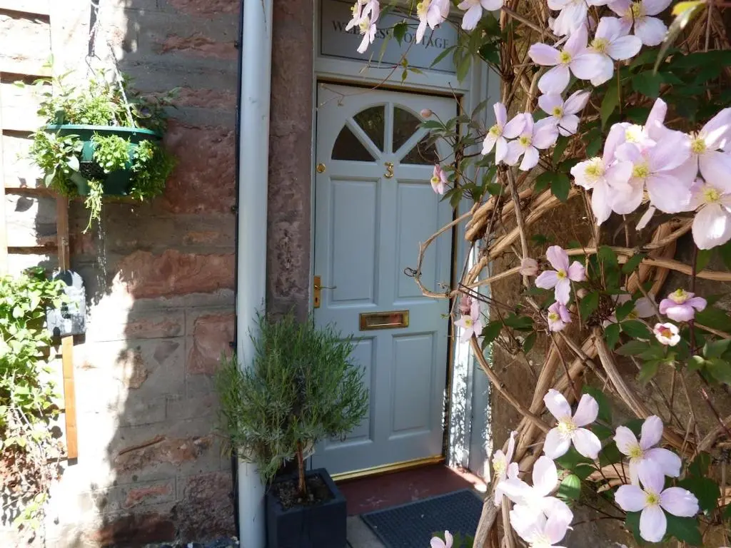 a door of a house with pink flowers at Wee Ness Cottage in Inverness