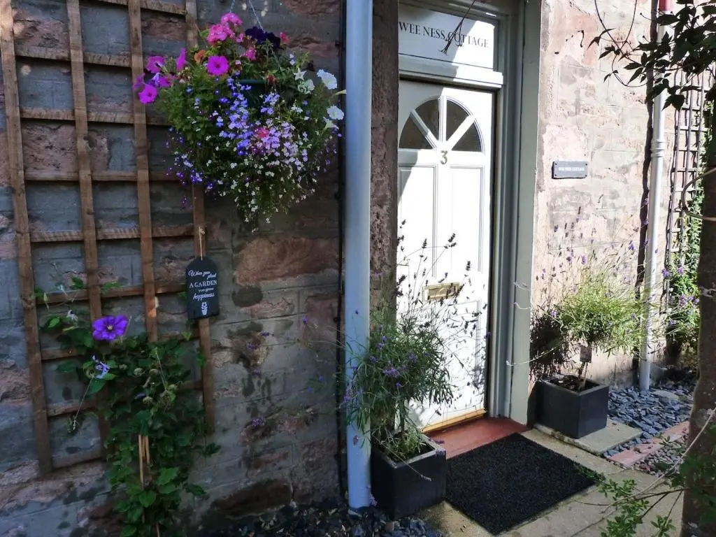 a door with flowers on the side of a building at Wee Ness Cottage in Inverness