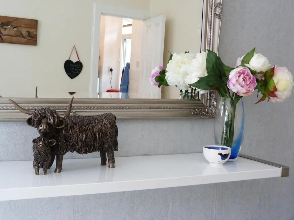 a statue of a dog on a shelf with a mirror at Wee Ness Cottage in Inverness