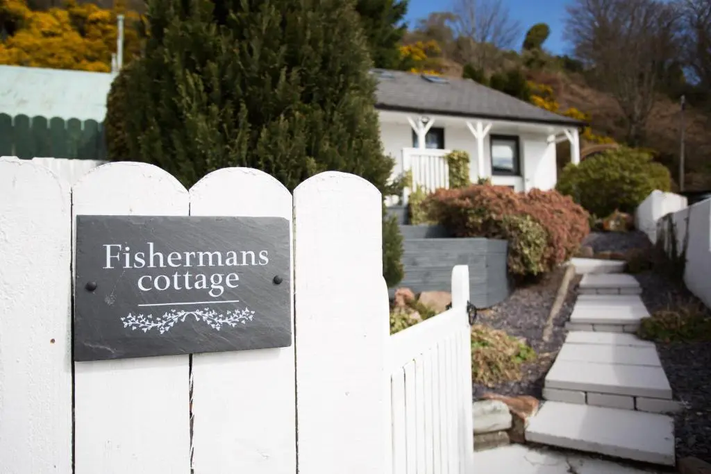 a sign on a white fence in front of a house at Fishermans in Inverness