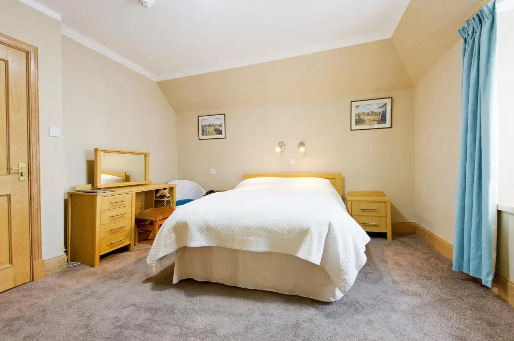 a bedroom with a bed and a dresser and a mirror at Nethercliffe Hotel in Wick