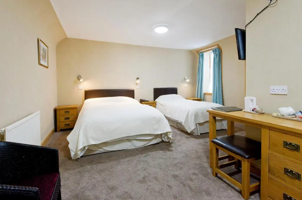 a hotel room with two beds and a desk and a desk at Nethercliffe Hotel in Wick