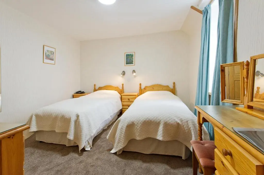 a bedroom with two beds and a desk at Nethercliffe Hotel in Wick
