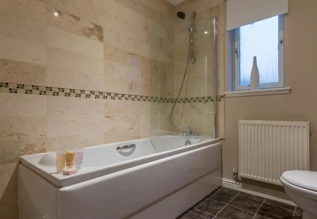 a bathroom with a tub and a toilet and a sink at Tigh na Lochan in Aviemore