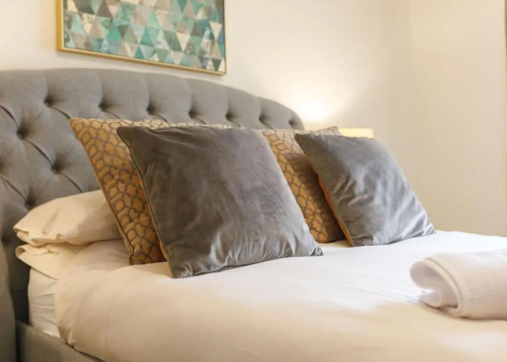 a bed with four pillows on top of it at The Old Dairy in Lairg