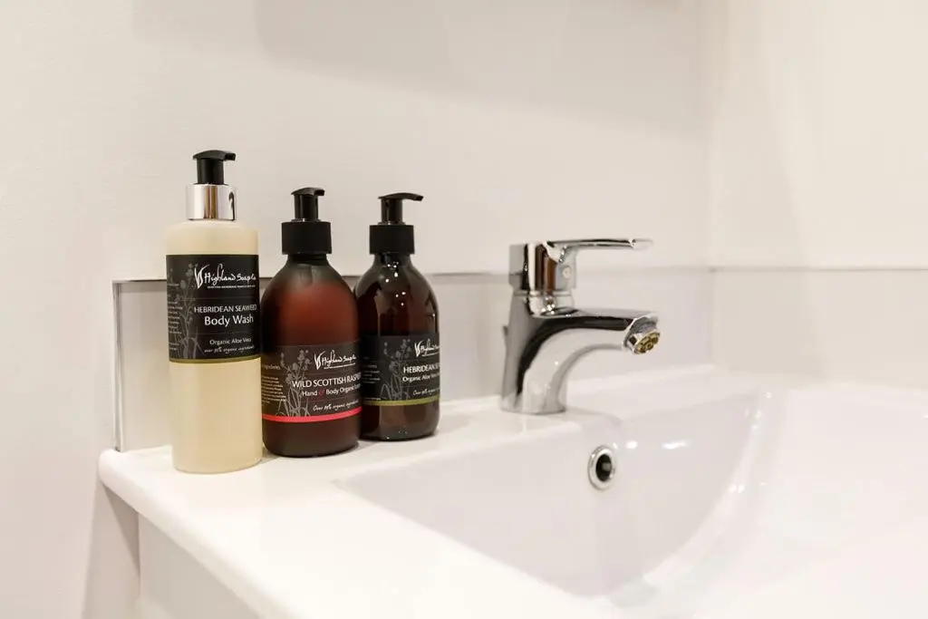 two bottles of alcohol sitting on a bathroom sink at The Old Dairy in Lairg