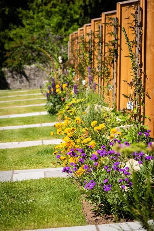 a garden with colorful flowers next to a fence at The Old Manse of Blair, Boutique Hotel & Michelin Restaurant in Blair Atholl