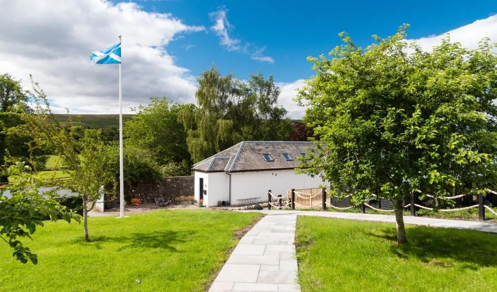 a house with a flag in the yard at The Old Manse of Blair, Boutique Hotel & Michelin Restaurant in Blair Atholl