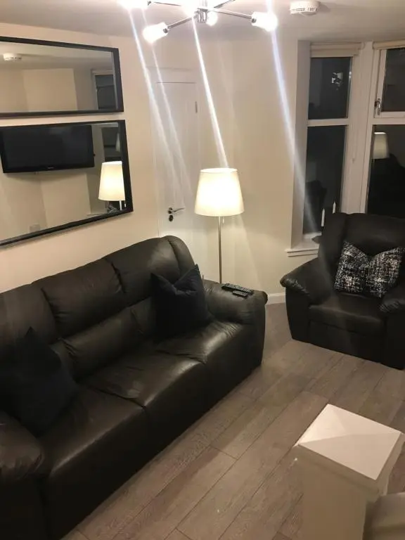 a living room with a black leather couch and a lamp at View Cottage in Inverness
