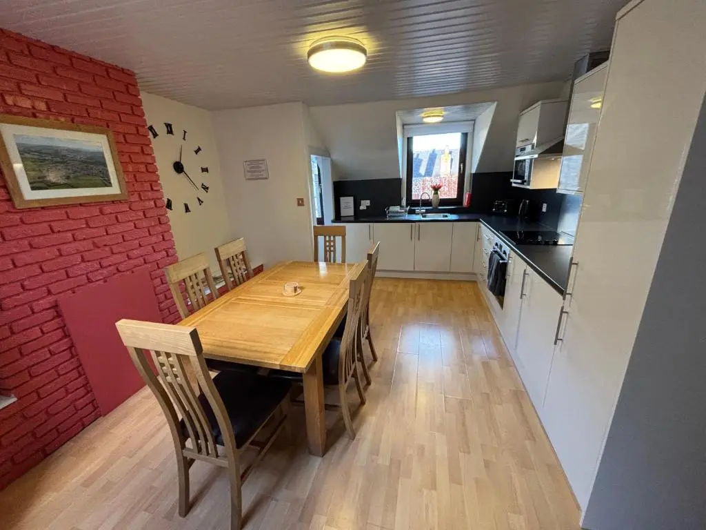 a kitchen with a wooden table and a red brick wall at The Coffee Pot accommodation in Dufftown
