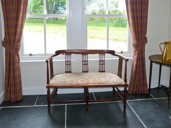 a wooden chair sitting in front of a window at Easter Urray Farmhouse in Muir of Ord