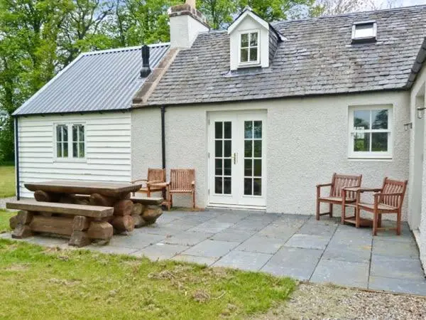 a white house with a picnic table and benches at Easter Urray Farmhouse in Muir of Ord