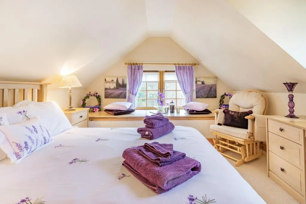 a bedroom with a bed with purple towels on it at Dunstaffnage Cottage in Grantown on Spey