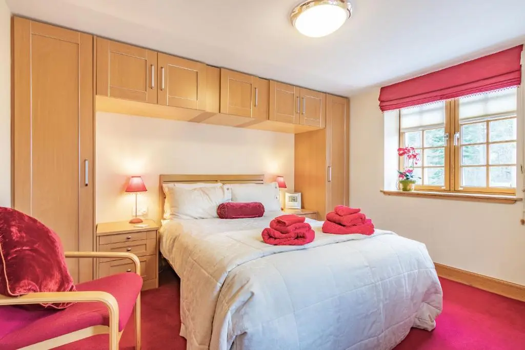 a bedroom with a large bed with red towels on it at Dunstaffnage Cottage in Grantown on Spey