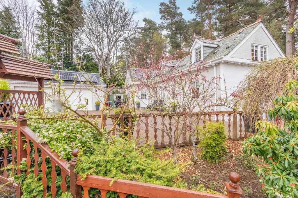 a house with a wooden fence in front of a garden at Dunstaffnage Cottage in Grantown on Spey