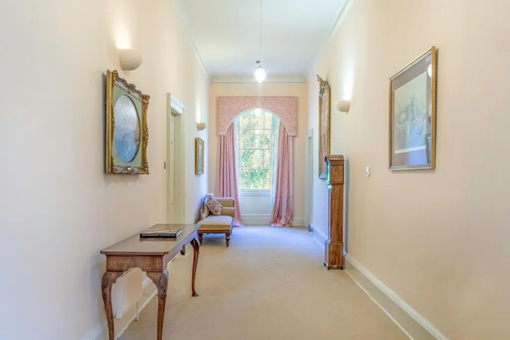 a hallway with a table and a chair and a window at Blervie House in Forres