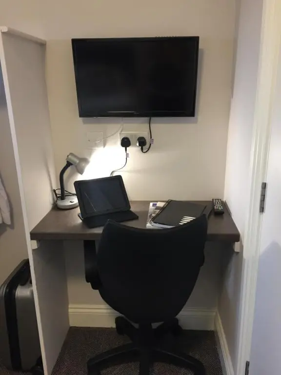 a desk with a laptop and a monitor and a chair at The Sidings Inverurie in Inverurie