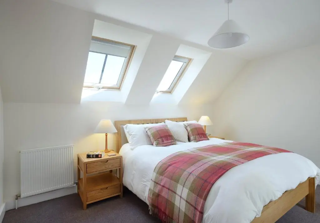 a bedroom with a bed and two windows at Osprey Lodge in Kingussie
