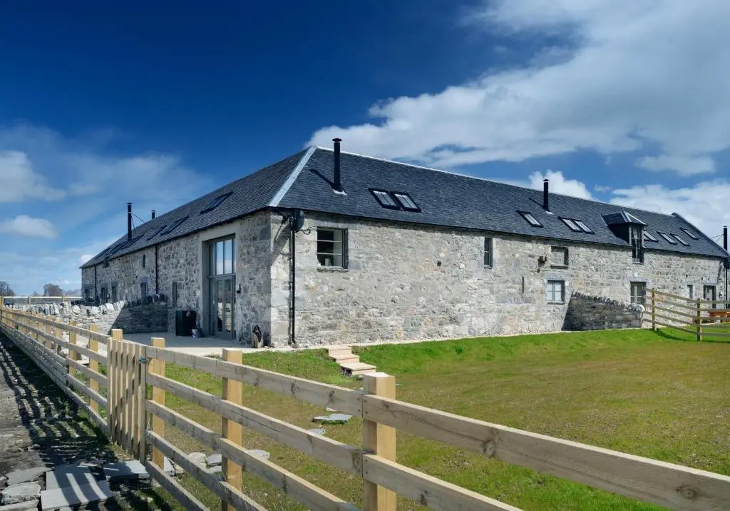 a stone building with a fence in front of it at Osprey Lodge in Kingussie