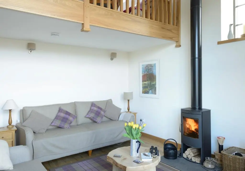 a living room with a couch and a wood stove at Osprey Lodge in Kingussie