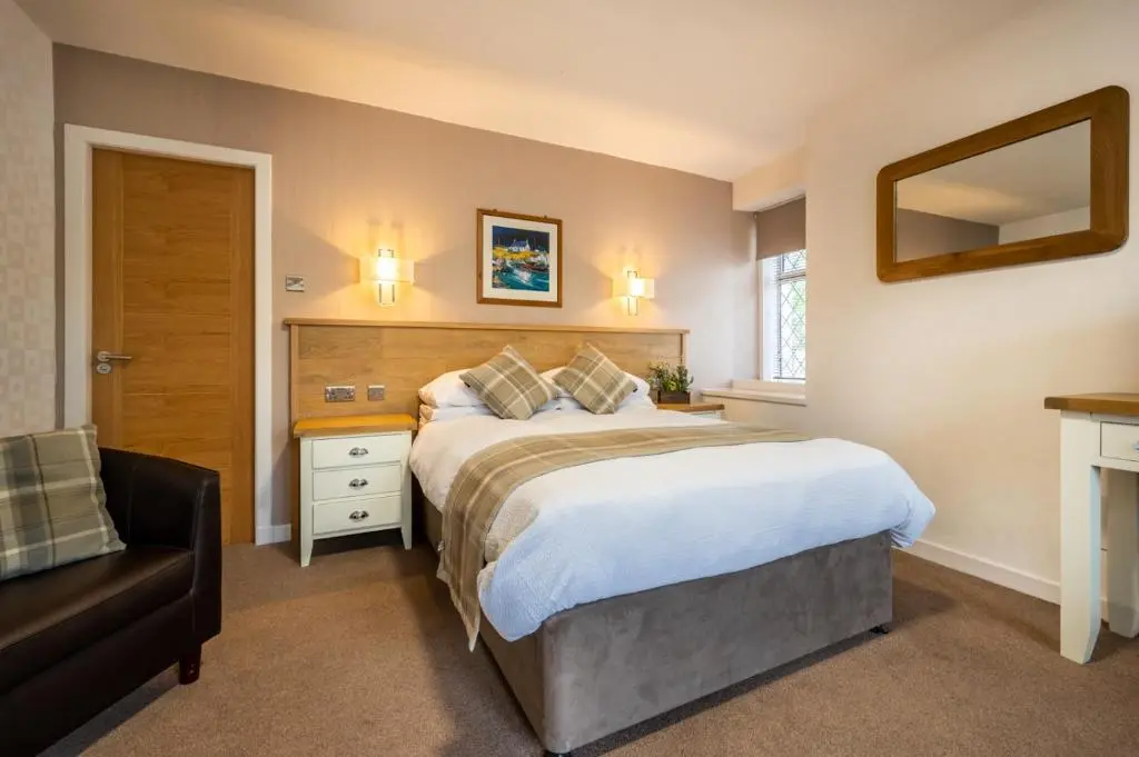 a bedroom with a large bed and a chair at Riverside in Ullapool