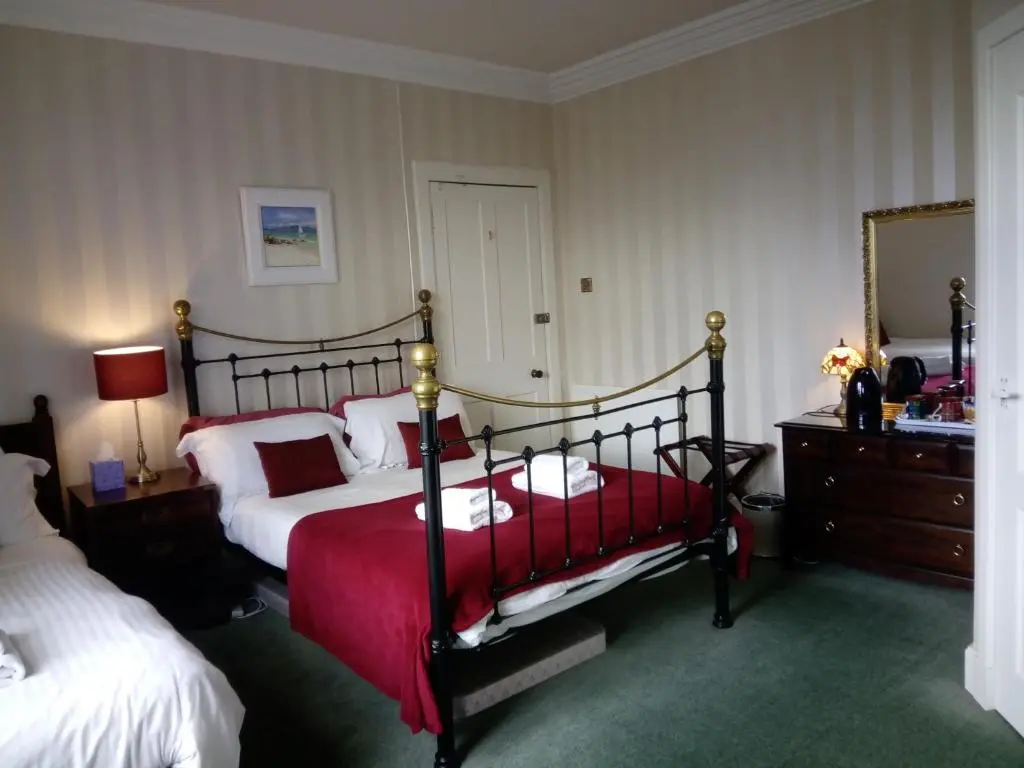 a bedroom with two beds and a mirror at Dunallan Guest House in Grantown on Spey