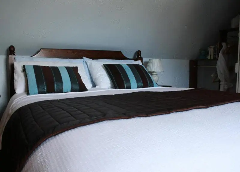 a bedroom with a large bed with white sheets and pillows at Dunallan Guest House in Grantown on Spey