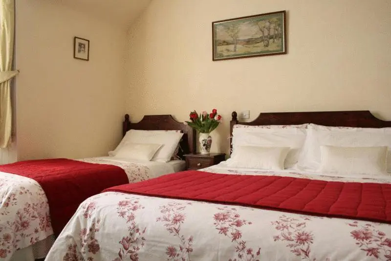a bedroom with two beds with red and white sheets at Dunallan Guest House in Grantown on Spey
