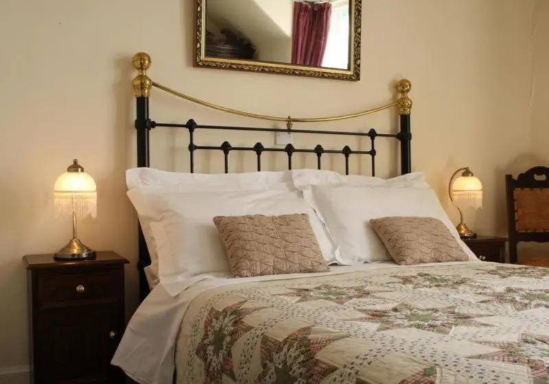 a bedroom with a bed with two lamps and a mirror at Dunallan Guest House in Grantown on Spey