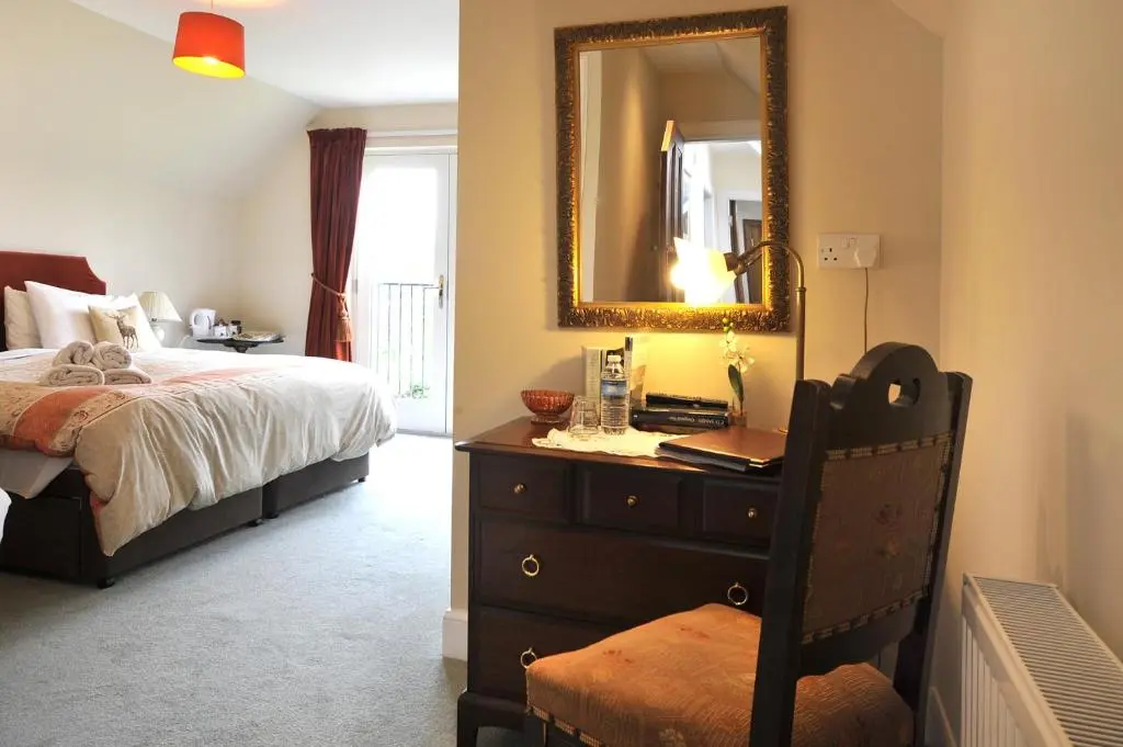 a bedroom with a bed and a dresser with a mirror at Dunallan Guest House in Grantown on Spey