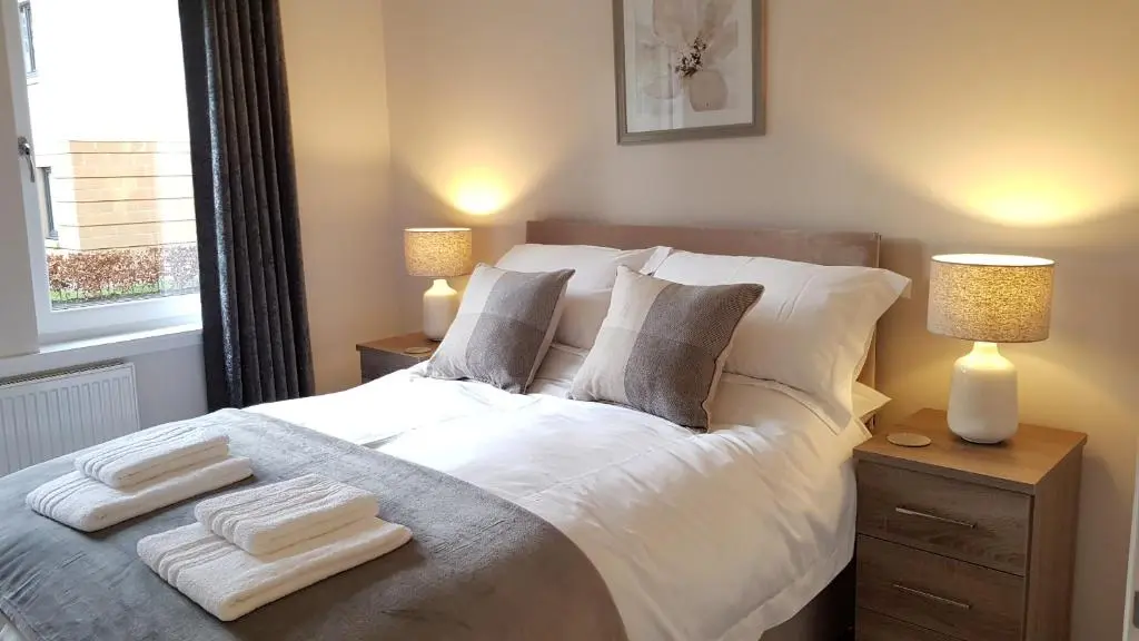 a bedroom with a bed with two lamps and towels on it at 23 Hedgefield House in Inverness