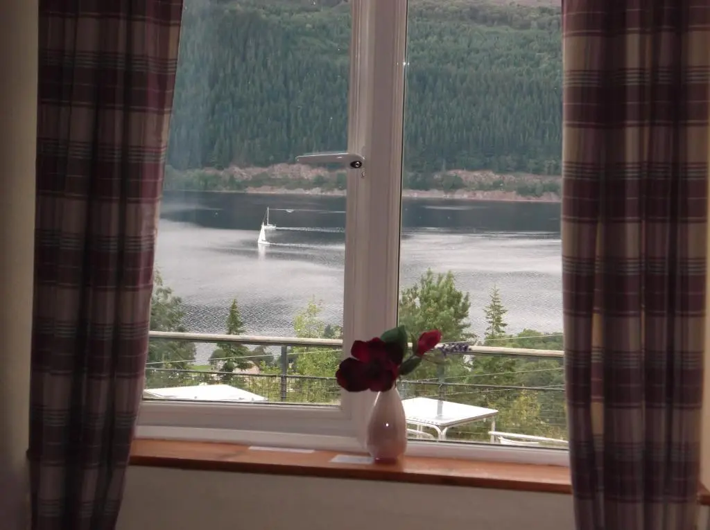 a window with a flower in a vase on a window sill at Foyers Roost in Foyers