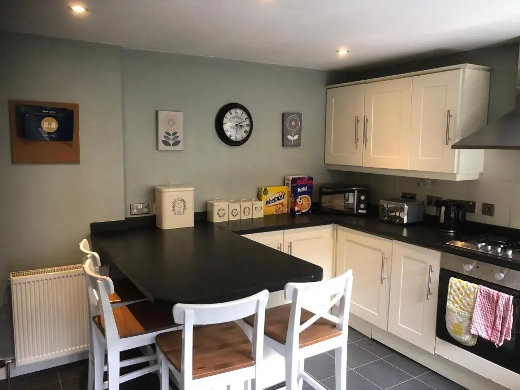 a kitchen with a table and chairs and a clock on the wall at Rose Cottage in Inverness