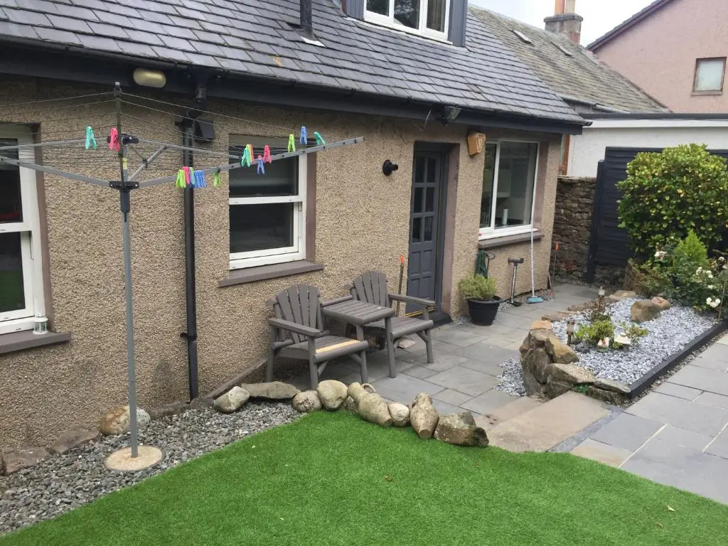 a garden with two chairs and a bench in front of a house at Rose Cottage in Inverness