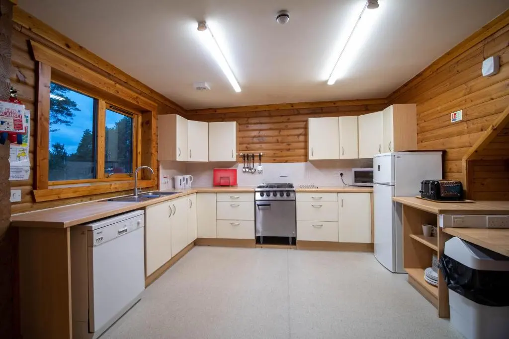 a kitchen with white appliances and wooden walls at Badaguish forest lodges and camping pods in Aviemore