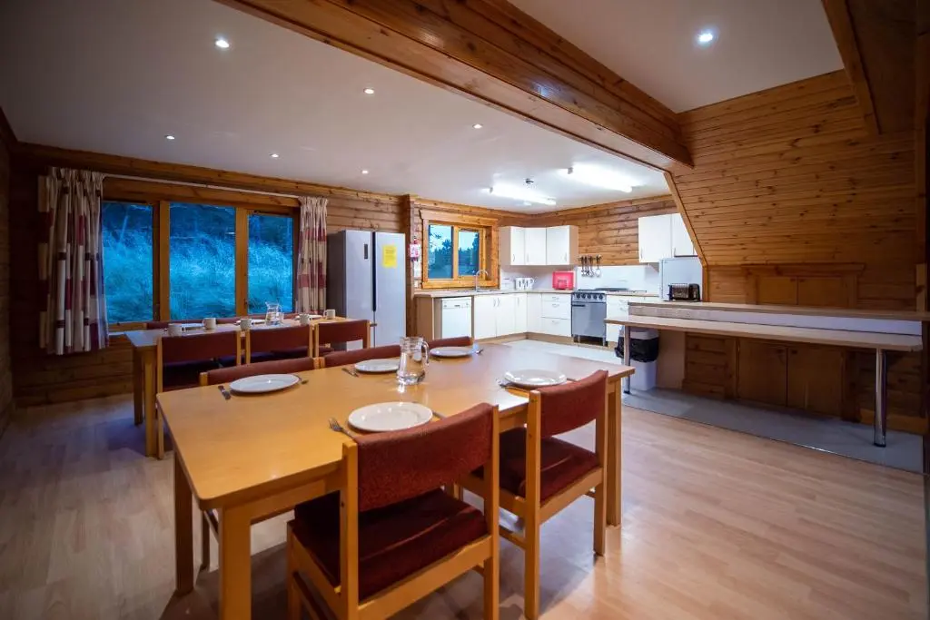 a kitchen and dining room with a wooden table and chairs at Badaguish forest lodges and camping pods in Aviemore