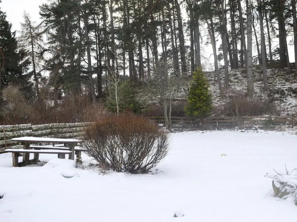 a picnic table in a snow covered park at West End Cottage in Carrbridge
