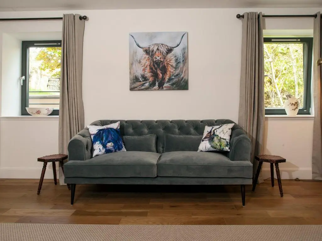 a living room with a couch and a picture of a bull at Strathspey Lodge in Duthil