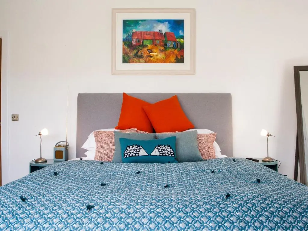 a bedroom with a bed with orange and blue pillows at Strathspey Lodge in Duthil