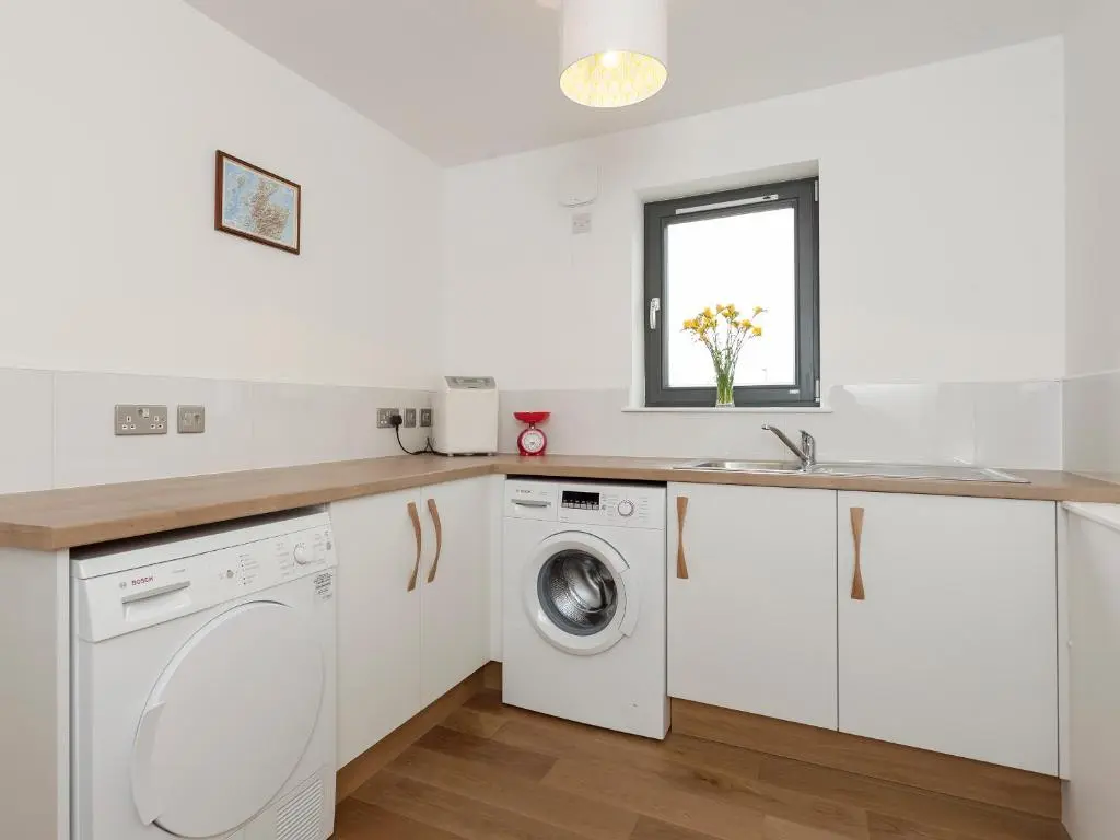 a white laundry room with a washer and dryer at Strathspey Lodge in Duthil