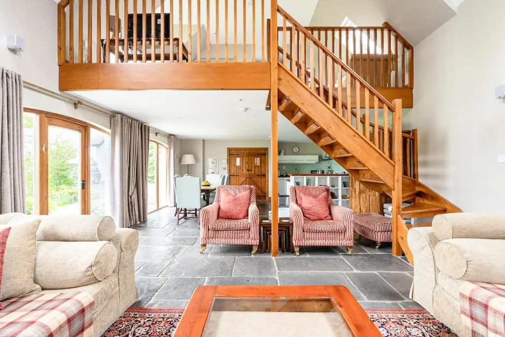 a living room with a staircase and a table and chairs at Coach House at Soilzarie in Blairgowrie