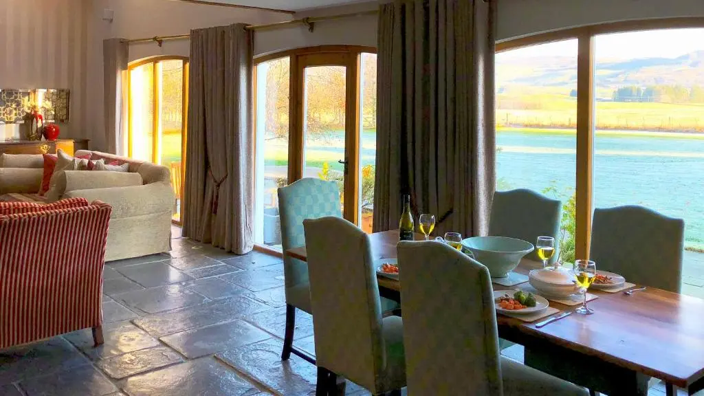 a dining room with a table and a view of the water at Coach House at Soilzarie in Blairgowrie