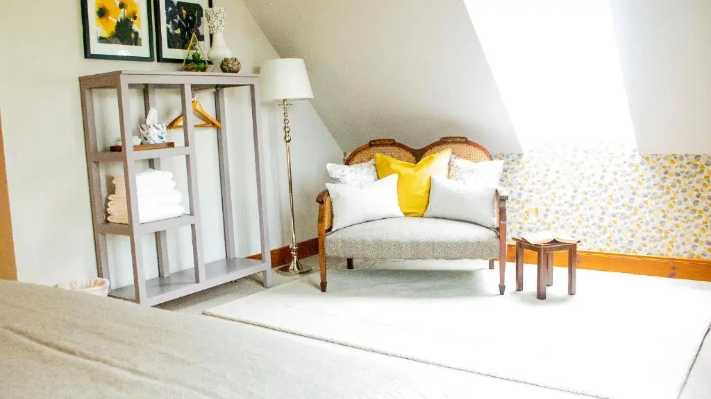 a bedroom with a bed and a chair with yellow pillows at Coach House at Soilzarie in Blairgowrie