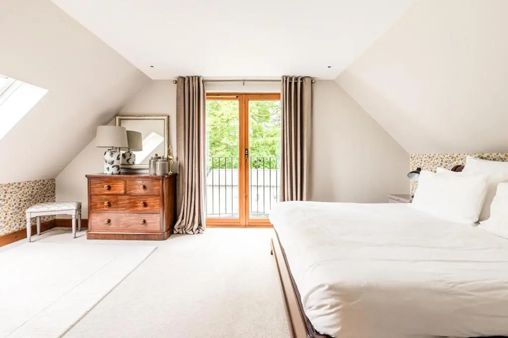 a white bedroom with a bed and a window at Coach House at Soilzarie in Blairgowrie