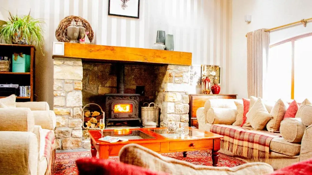 a living room with a stone fireplace and a couch at Coach House at Soilzarie in Blairgowrie
