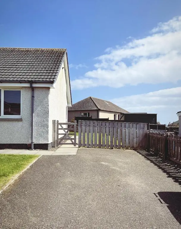 a house with a wooden fence next to a house at Malva - Modern 2 Bedroom Bungalow in Wick Sleeps 4 with private parking - NC500 Route in Wick